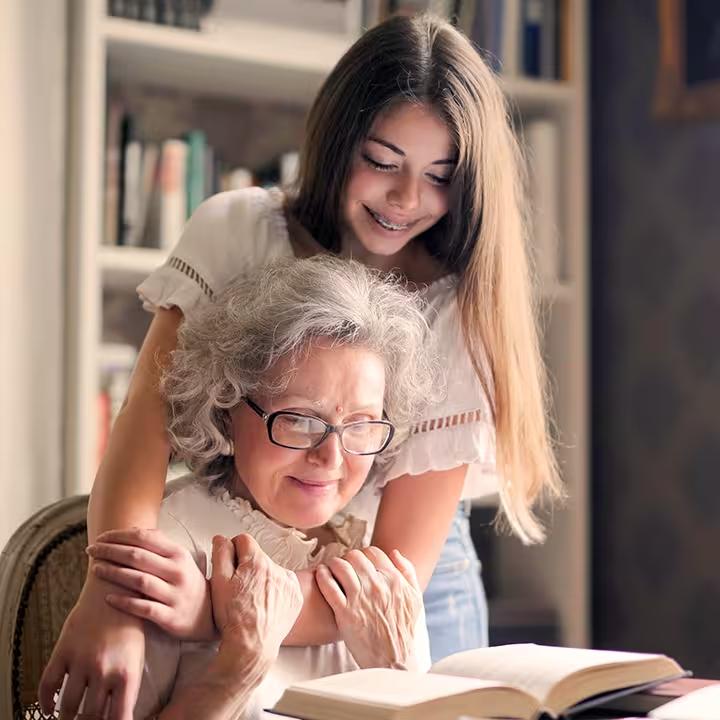 Granddaughter smiling next to her grandmother while reading